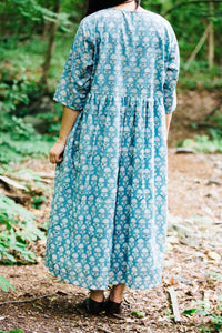 Person wearing a blue floral block print dress standing in a forest