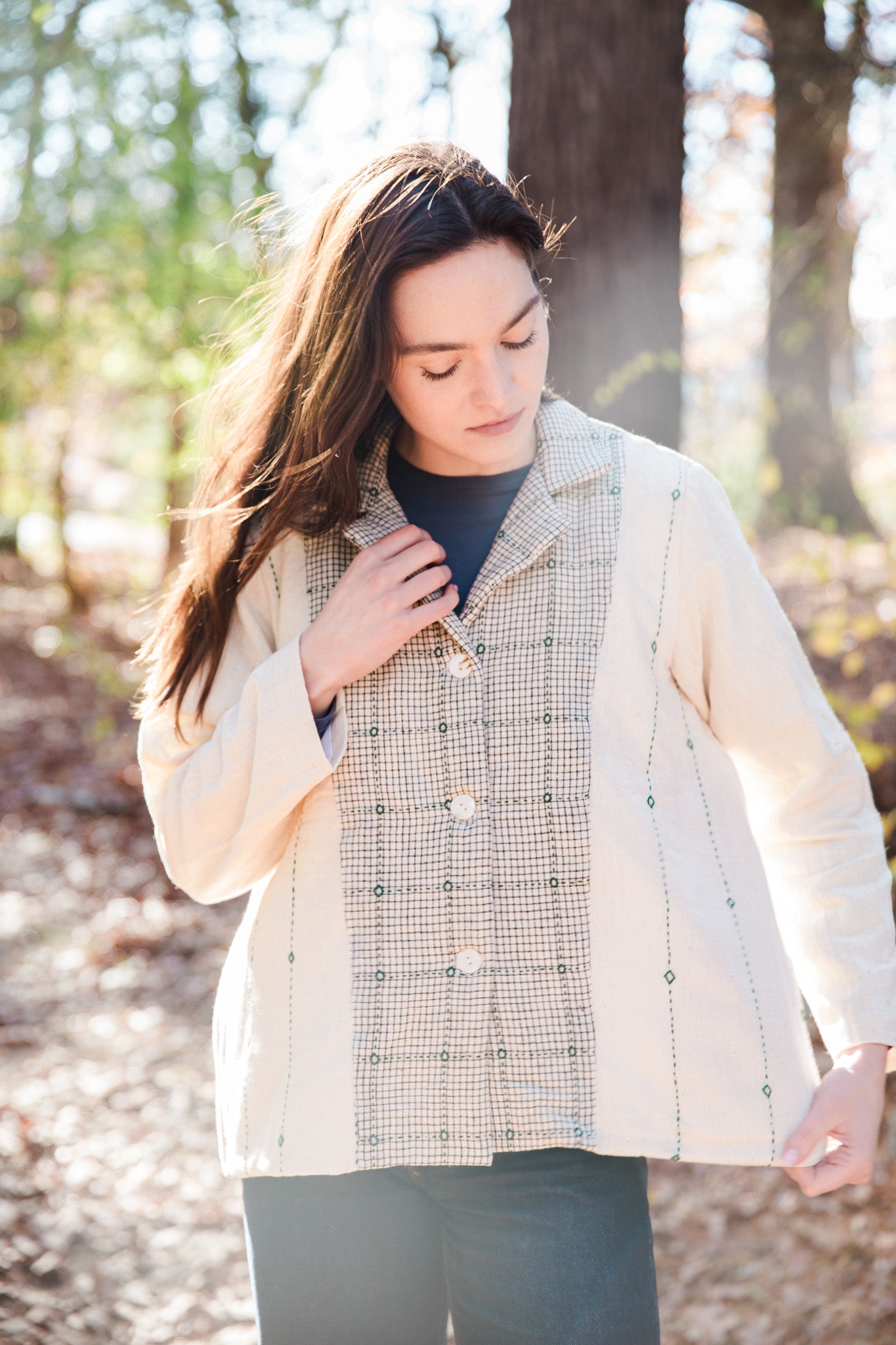 Woman wearing a checkered handloom cotton jacket in a forest setting